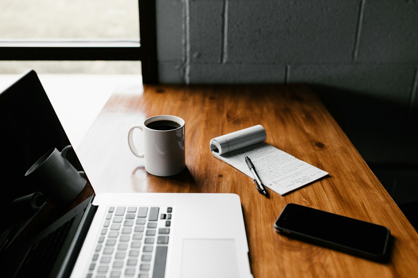 Laptop on a desk with notebook and coffee, representing planning a small business website